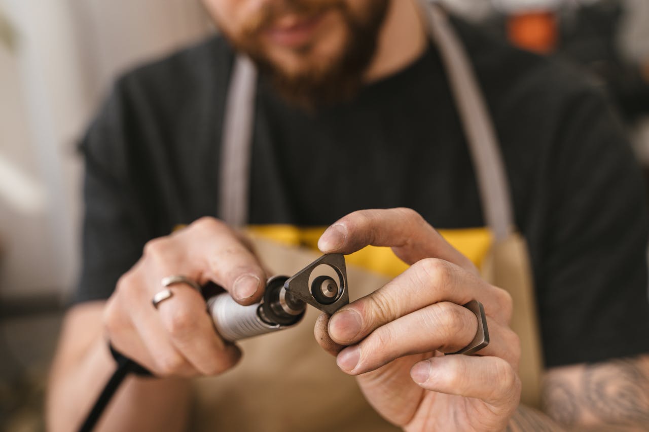 Close-up of a craftsman using a rotary tool for precise metalworking. Focus on craftsmanship.