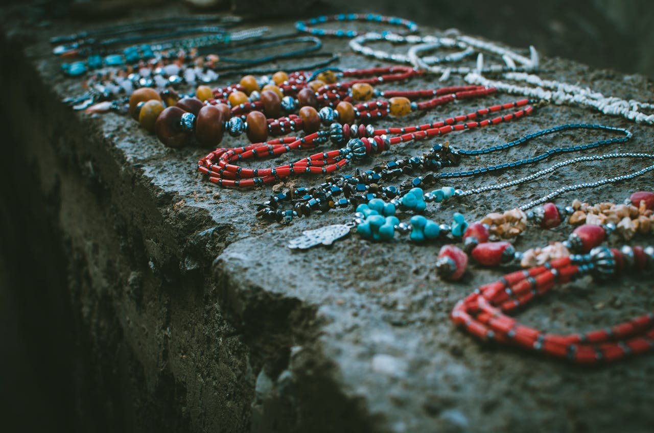 Vibrant beaded necklaces displayed outdoors on a rustic stone surface.
